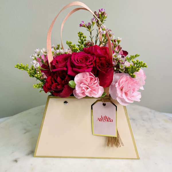 Pink and red rose arrangement in a cream gift bag with ribbon handles
