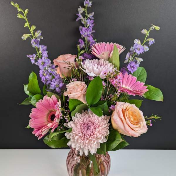 Pink and lavender flowers arranged in a glass vase