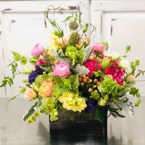 Mixed bouquet in a dark rectangular container with pink, yellow, white, and purple blooms