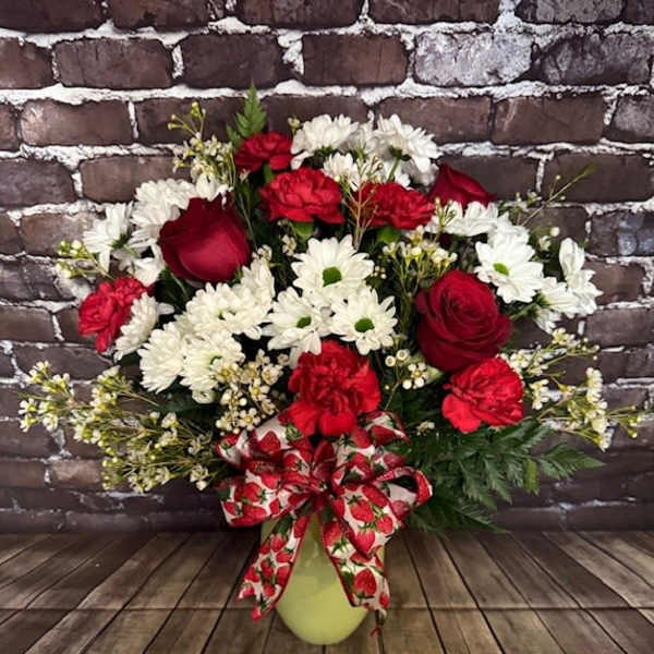 Red roses and white daisies in a vase with a strawberry-patterned bow