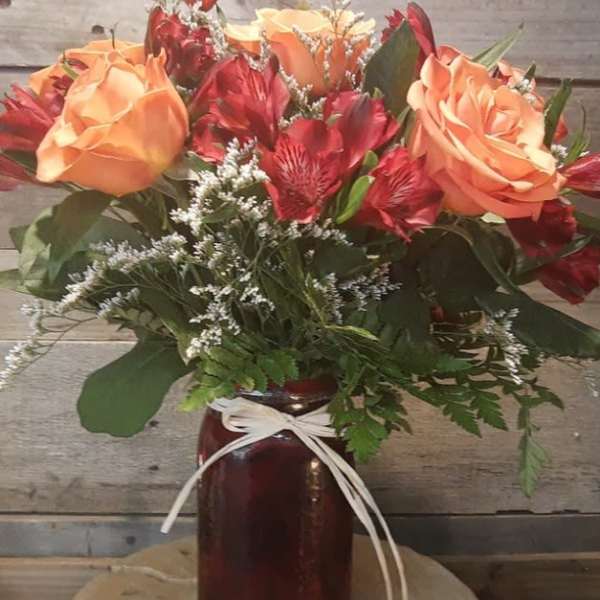 Bouquet of peach roses and red alstroemeria in a dark vase