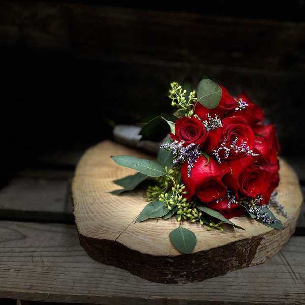 Red rose bouquet with eucalyptus on a wood slice