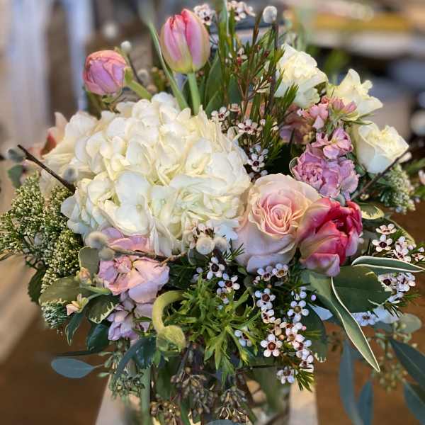 Bouquet of white hydrangeas, pink roses, and tulips in a glass vase