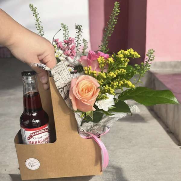 Bouquet with pink and peach roses in a kraft gift box beside a maraschino cherry bottle