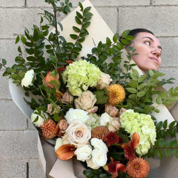 Large bouquet of pale roses, hydrangeas, and orange blooms with greenery