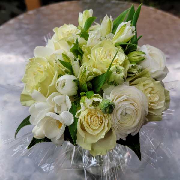 Bouquet of white and pale yellow flowers wrapped in clear plastic