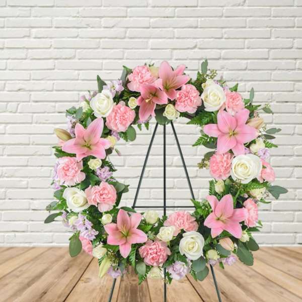 Pink and white floral wreath on a black stand