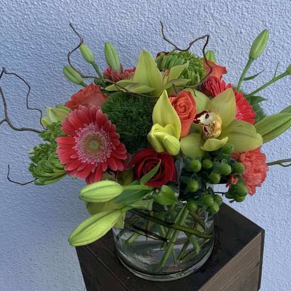 Mixed bouquet with lilies, gerbera daisies, roses, and orchids in a glass vase