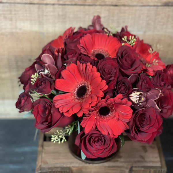 Bouquet of red roses and gerbera daisies in a low container