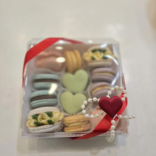 Box of assorted macarons tied with a red ribbon and pearl heart decoration