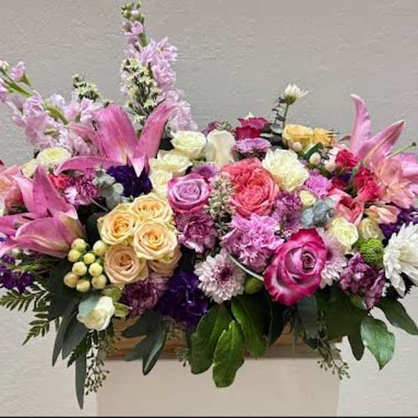 Large mixed bouquet of pink, purple, and white flowers in a container