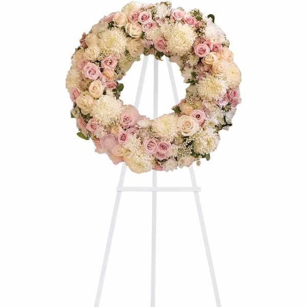 Round floral wreath of pink and cream roses on a white stand