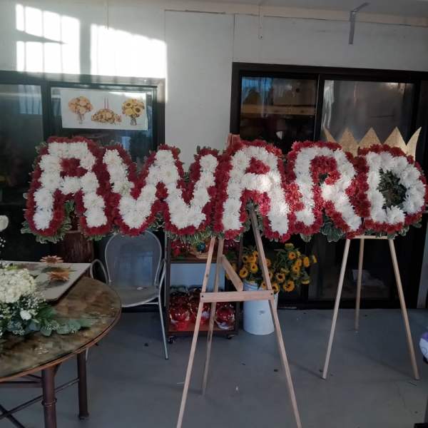 Large floral letters on easels spelling a name in red and white flowers