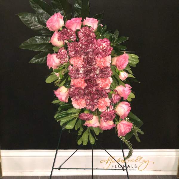 Standing floral spray with pink roses and carnations on a black easel