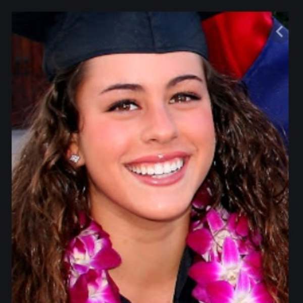 Woman wearing a magenta orchid lei and graduation cap