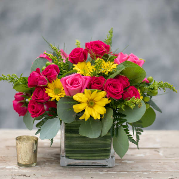 Pink roses and yellow daisies in a square glass vase