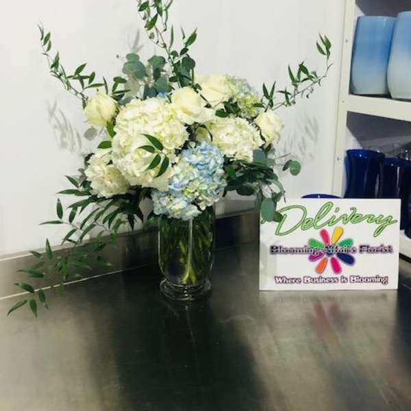 White and pale blue flowers in a glass vase with long greenery