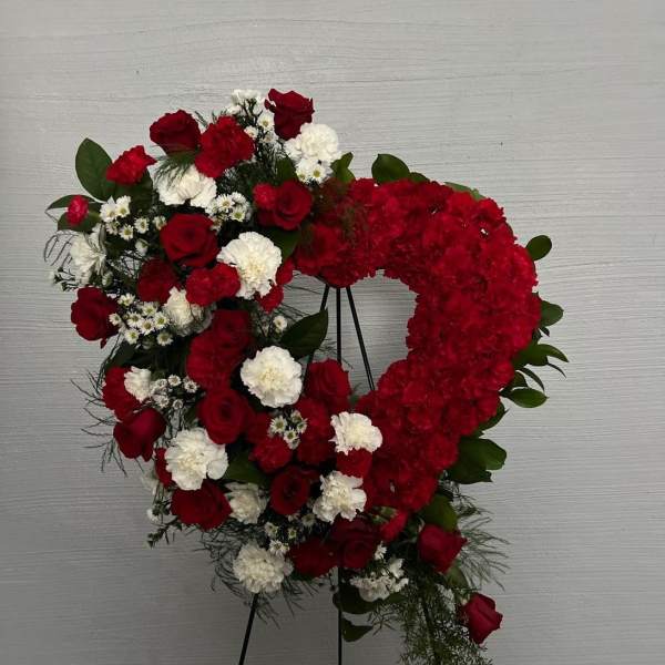 Heart-shaped floral wreath with red and white flowers on a stand