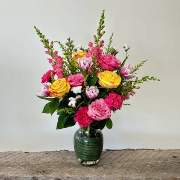 Mixed pink and yellow bouquet in a green glass vase
