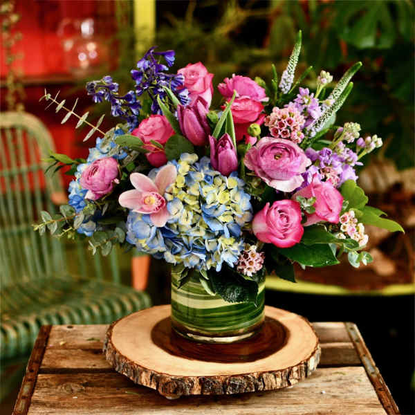 Pink and blue mixed flower arrangement in a striped glass vase