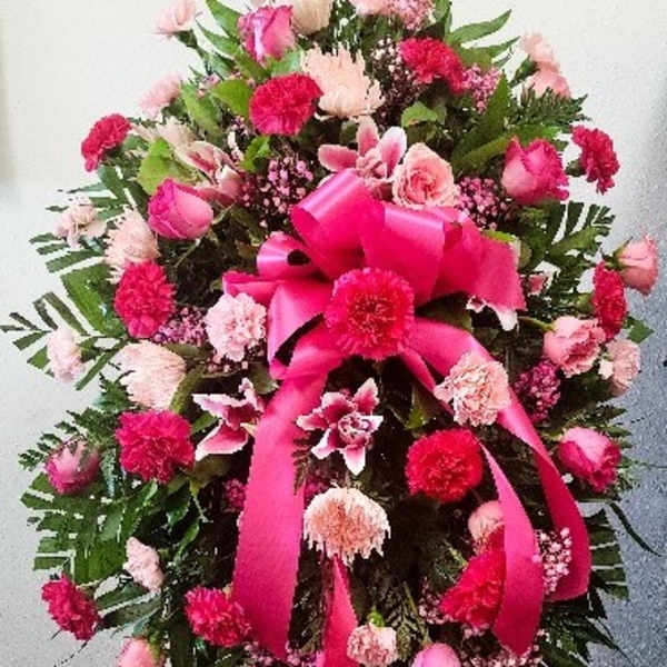 Pink and red funeral spray with ribbon on a standing easel