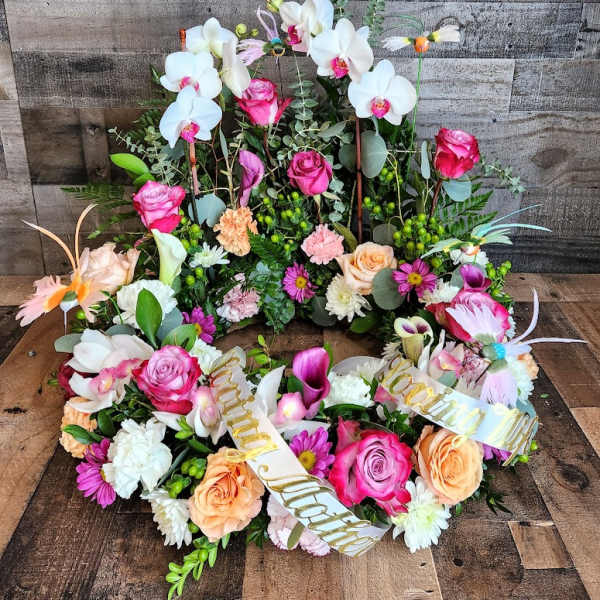 Sympathy wreath of pink roses, white orchids, and mixed blooms with a Loving Mother ribbon.