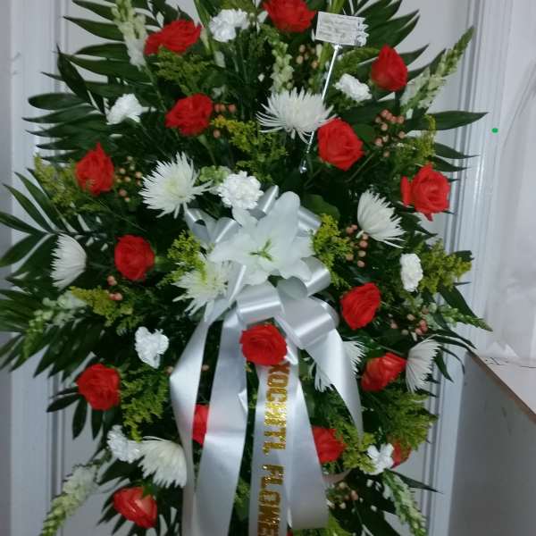 Standing floral wreath with red and white flowers on a metal easel