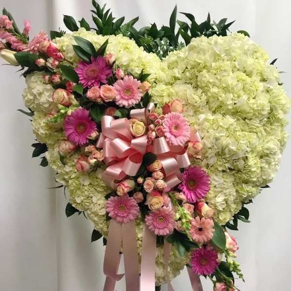 Heart-shaped floral spray with pink gerberas and roses on a stand
