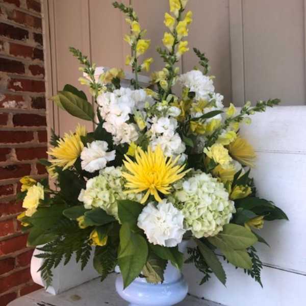 Yellow and white floral arrangement in a light blue vase
