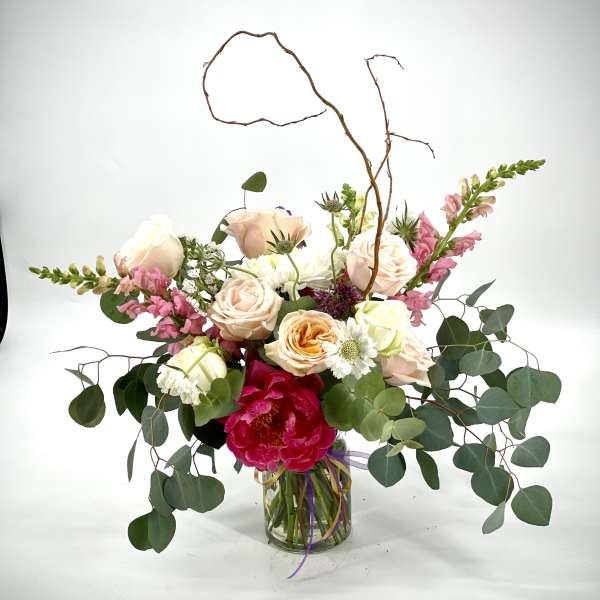 Mixed bouquet of roses, peonies, and snapdragons in a glass vase