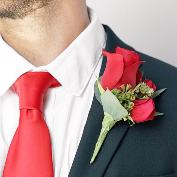 Red rose boutonniere on a suit lapel with a red tie
