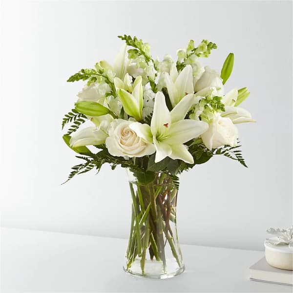 White lilies and roses arranged in a clear glass vase