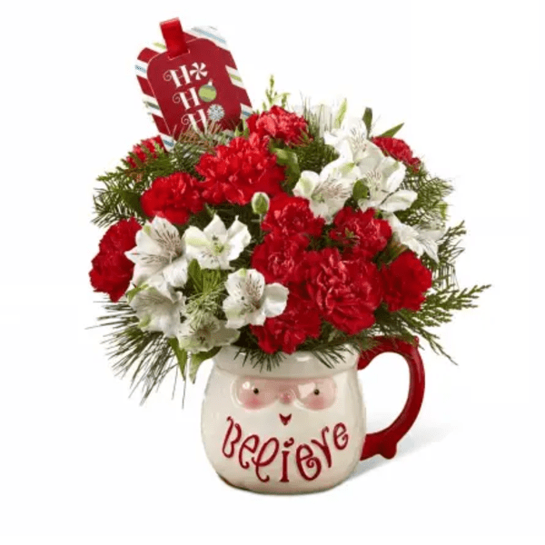 Red and white floral arrangement in a mug with a holiday tag