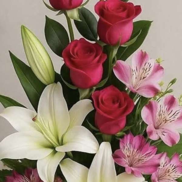 Tall arrangement of red roses, white lilies, and pink blooms in a wooden box with a burlap bow