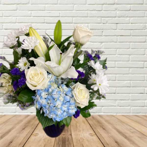 White lilies, roses, and blue hydrangea in a vase