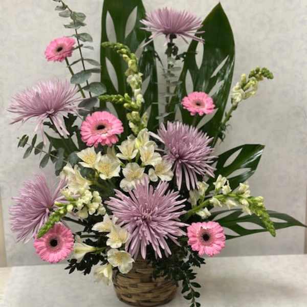 Pink and lavender flowers arranged in a wicker basket