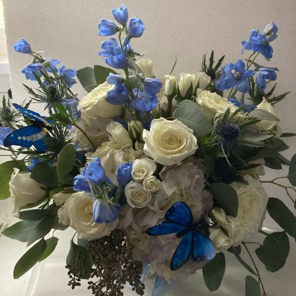 Bouquet of white roses and blue flowers with butterfly accents