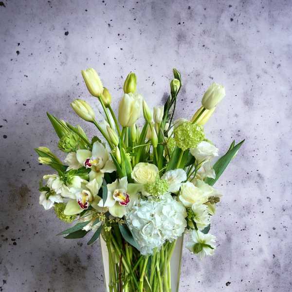 White and pale green floral arrangement in a clear glass vase