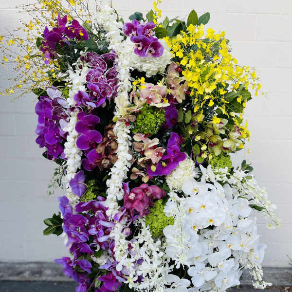 Large standing arrangement of purple, white, and yellow orchids