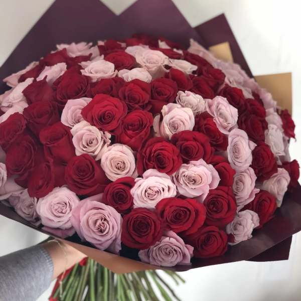 Large bouquet of red and pale pink roses wrapped in dark paper