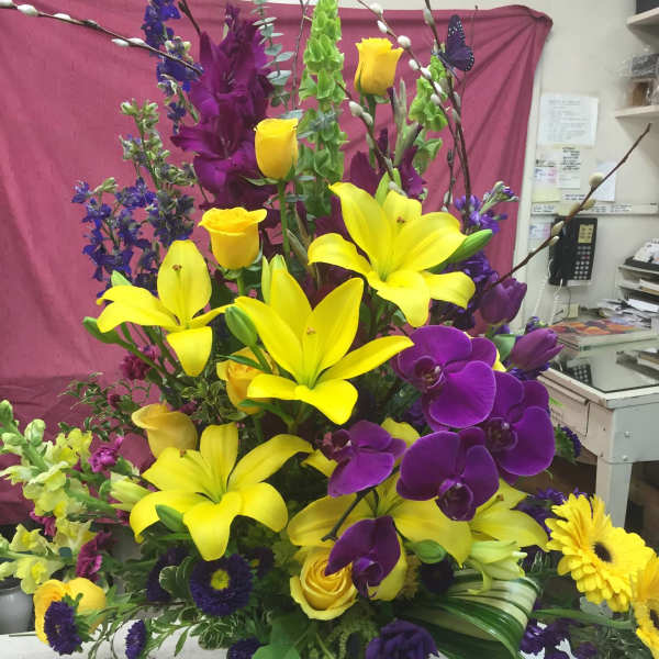 Tall bouquet with yellow lilies, purple orchids, and yellow roses