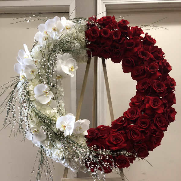 Heart-shaped floral wreath with red roses and white orchids on an easel