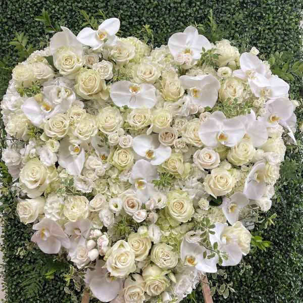 Heart-shaped white floral arrangement on an easel