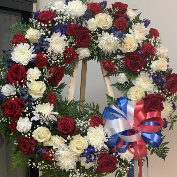 Large floral wreath with red, white, and blue flowers on an easel