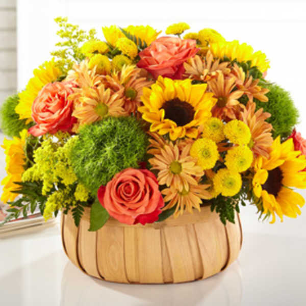 Mixed bouquet in a wooden basket with sunflowers and roses