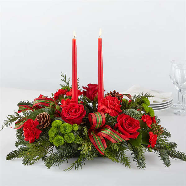Red floral centerpiece with two lit candles and plaid ribbon