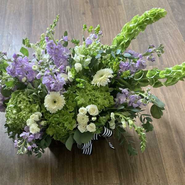 Low floral arrangement with lavender blooms, white flowers, and bright green accents