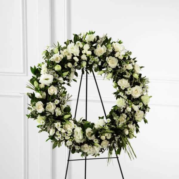 White floral wreath on a black stand