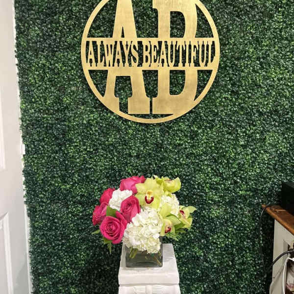 Pink roses and white flowers in a square glass vase on a pedestal