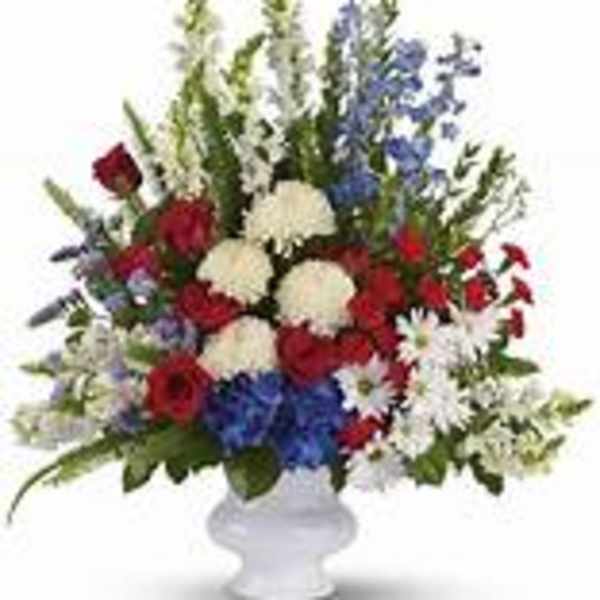 Red, white, and blue floral arrangement in a white vase